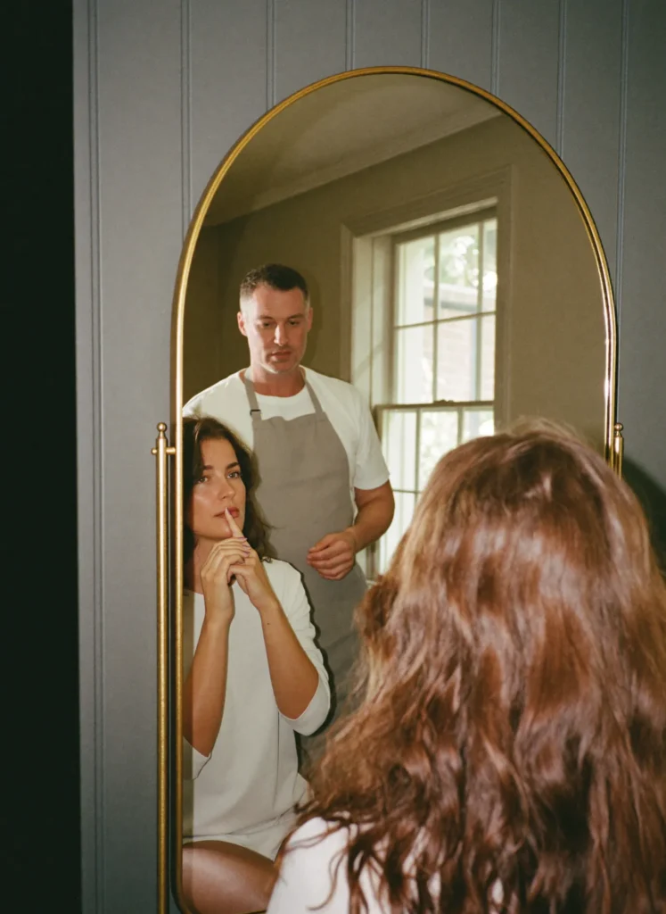 Vrouw bekijkt haar haar in de boogspiegel terwijl de kapper advies geeft