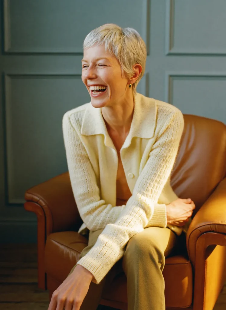 Laughing woman with a silver pixie cut in the salon chair