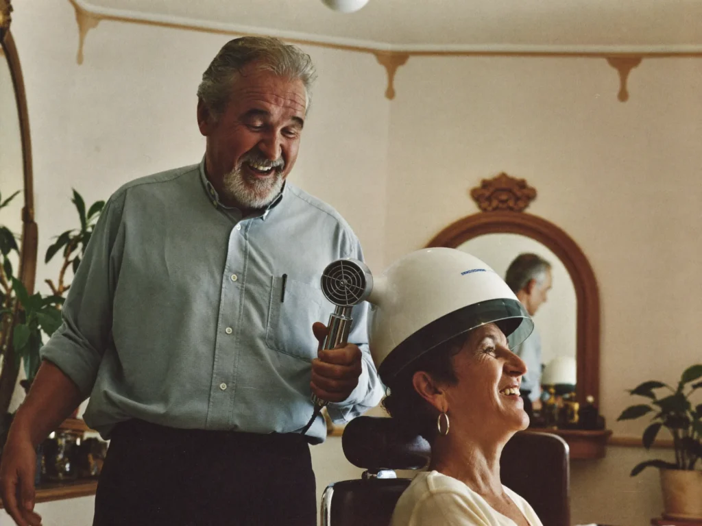 Willem laughing with a client under the hood dryer in the expanded salon, early nineties